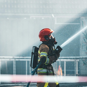 A brave firefighter operates a fire hose, wearing protective gear during a training exercise outdoors.