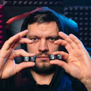 Man in hoodie holding alphabet keys spelling 'SCAM', symbolizing cybersecurity threat.